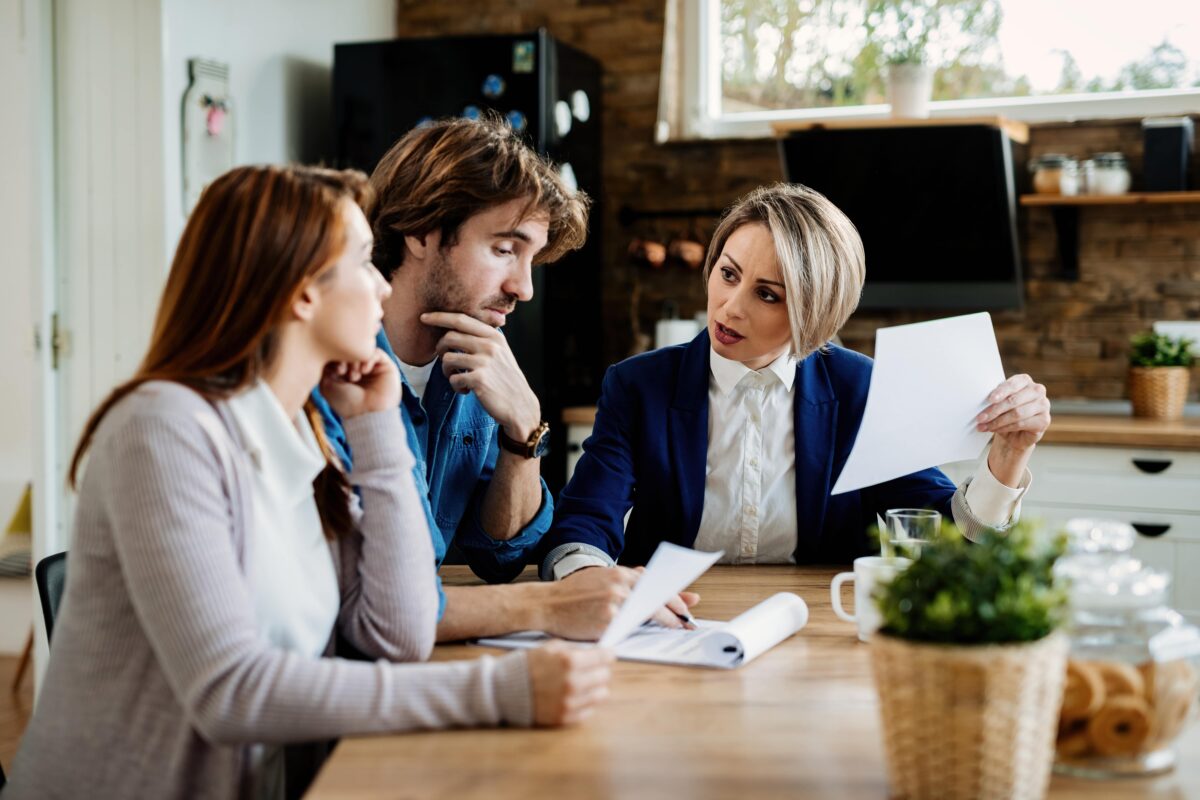 financial-advisor-communicating-with-young-couple-while-going-through-their-financial-reports-meeting-home-min-1200x800.jpg